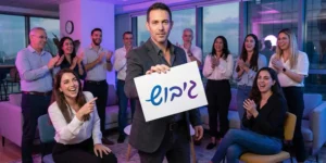 אסף סלומון אמן חושים בערב גיבוש לעובדים עם שלט גיבוש וצוות צוחק.